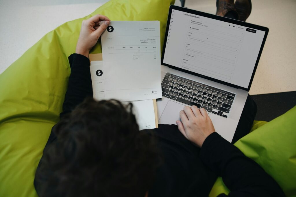Rechnungen sammeln, um Coworking Kosten absetzen zu können, am Laptop eines Freelancers