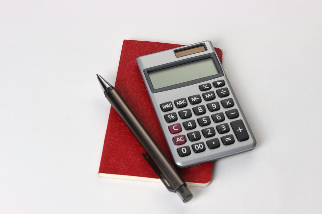 Stundensatz kalkulieren: Taschenrechner, Notizbuch und Laptop auf dem Schreibtisch einer Selbstständigen