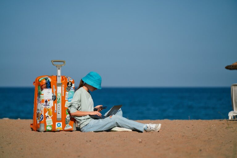 Workation Regelung: Mitarbeiterin arbeitet mit Laptop an einem Urlaubsort